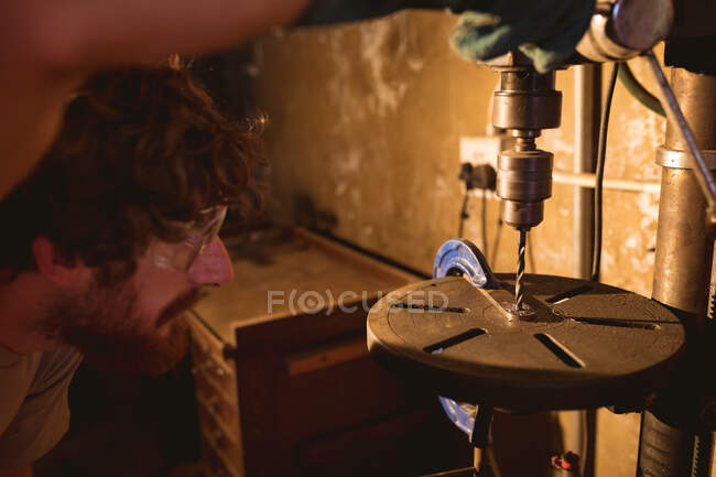 Caucasian blacksmith making hole on metal with machinery in industry. forging, metalwork and manufacturing industry. — Stock Photo