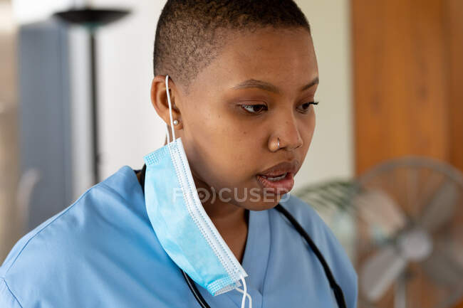 Médico afroamericano con máscara facial en el hospital durante el covidio-19. servicios sanitarios y pandemia. - foto de stock