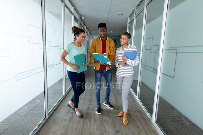 Багаторасові чоловіки і жінки-колеги в нещасних випадках обговорюють файл в коридорі офісу. креативний бізнес і сучасний офіс . — стокове фото