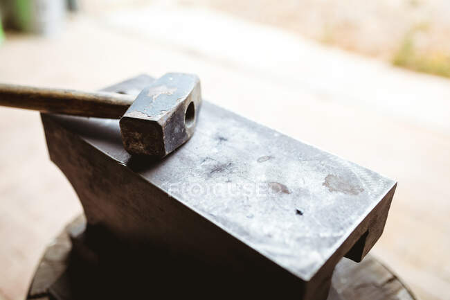 Großaufnahme von Hammer mit Holzstiel auf Amboss in der verarbeitenden Industrie. Schmiede-, Metall- und Fertigungsindustrie. — Stockfoto