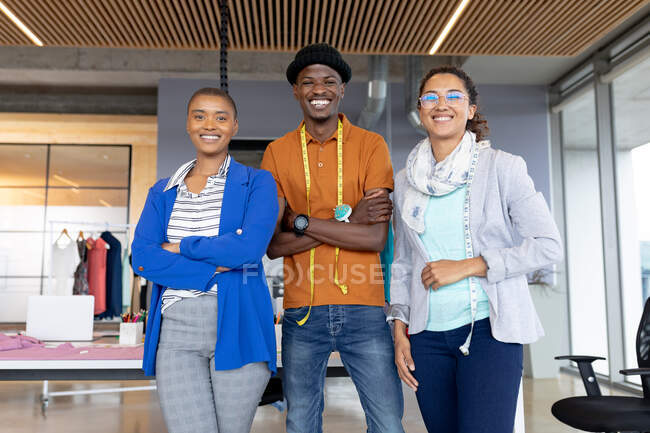 Portrait of cheerful multiracial female and male fashion designers in casuals standing at office. creative design business, modern office and fashion. — Stock Photo