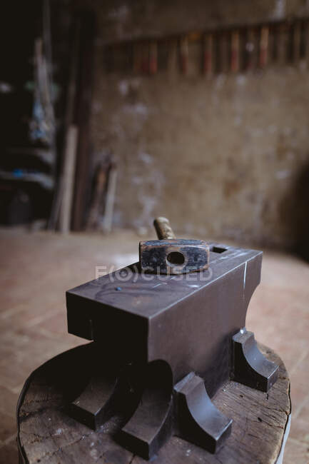 Молот з дерев'яною ручкою тримається на ковадлі у виробничій промисловості. кування, металообробка та промисловість . — стокове фото