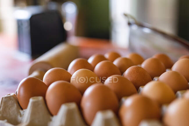 Close-up of fresh brown eggs in carton on table in kitchen at home. organic and healthy eating. — Stock Photo
