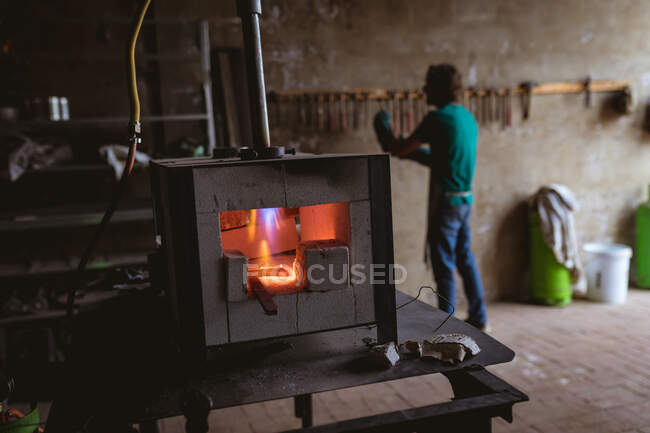 Las llamas en el horno mientras herrero trabajando en segundo plano en la industria. forja, metalurgia e industria manufacturera. - foto de stock