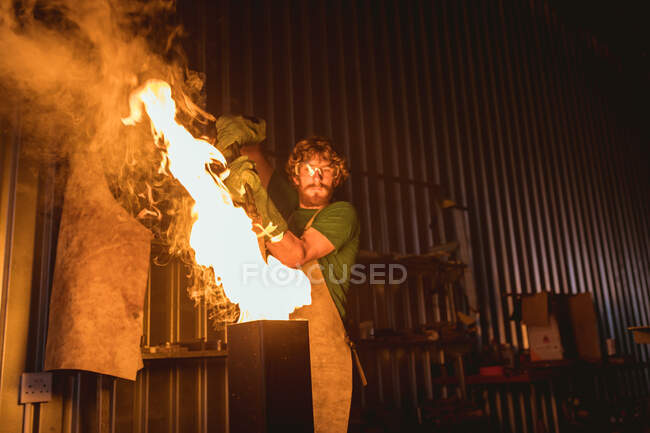 Schmied setzt Metall in Brand, während er in der verarbeitenden Industrie schmiedet. Schmiede-, Metall- und Fertigungsindustrie. — Stockfoto