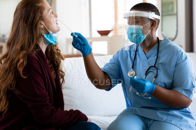 Doctora en mascarilla protectora tomando la prueba de hisopo de la mujer en la clínica durante la crisis del coronavirus. servicios sanitarios, prevención de enfermedades y pandemia. - foto de stock
