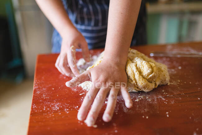 In der heimischen Küche knetet eine Frau Teig auf einem Holztisch. Lebensstil und gesunde Ernährung. — Stockfoto