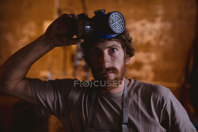 Portrait of bearded caucasian blacksmith with gas mask in manufacturing industry. forging, metalwork and manufacturing industry. — Stock Photo