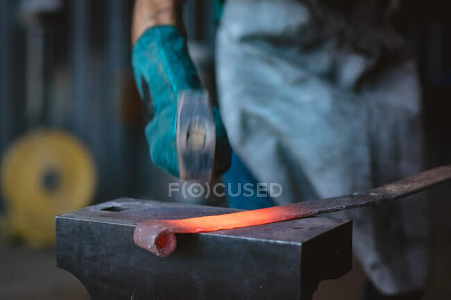 Cropped image of blacksmith in protective glove forging with hammer on anvil in industry. forging, metalwork and manufacturing industry. — Stock Photo