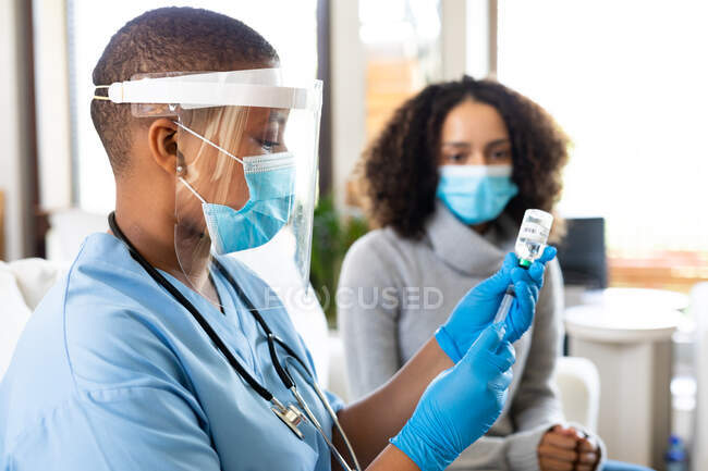 Femme médecin dans une seringue protectrice de remplissage de masque facial avec le vaccin en clinique pendant la covide-19. services de santé, prévention des maladies et pandémie. — Photo de stock