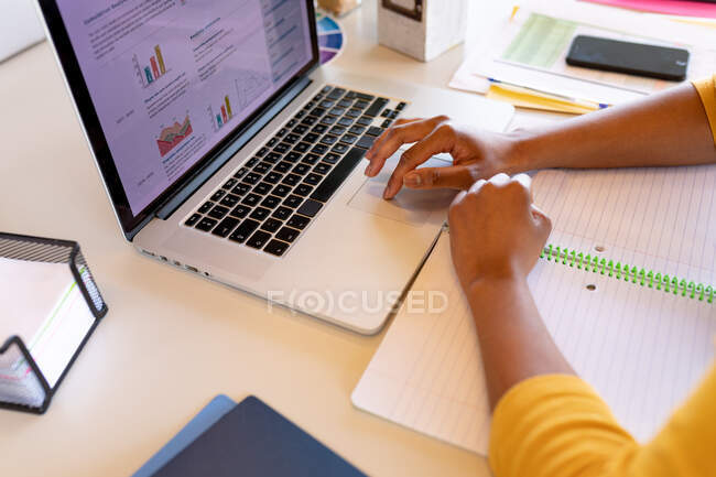 Cropped hands of businesswoman working on laptop at desk in creative office. creative business, office workplace and wireless technology. — Stock Photo