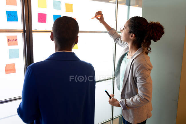 Les femmes d'affaires multiraciales planifient une stratégie d'entreprise sur des notes collantes colorées dans un bureau créatif. entreprise créative, bureau moderne, remue-méninges et plan d'affaires. — Photo de stock