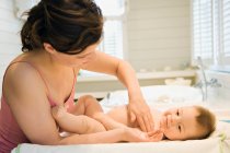Mother and naked baby with milky cleanser in her hand — Stock Photo
