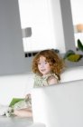 Портрет маленької дівчинки-імбируси, що сидить на дивані — стокове фото