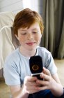 Pequeno menino ruivo com sardas usando telefone celular — Fotografia de Stock
