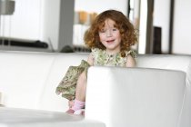 Portrait de petite rousse assise sur un canapé — Photo de stock