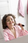 Little girl in bathroom brushing hair in front of mirror — Stock Photo