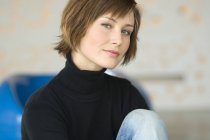 Portrait of woman with short hair sitting and looking at the camera — Stock Photo