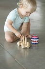 Piccolo ragazzo biondo che gioca sul pavimento con i giocattoli — Foto stock