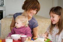 Mulher e 2 crianças na mesa de café da manhã — Fotografia de Stock