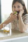 Retrato de menina comendo maçã e olhando para a câmera — Fotografia de Stock