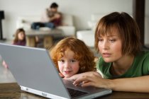 Woman and little girl using laptop computer — Stock Photo