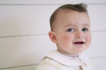 Portrait de mignon bébé garçon souriant contre le mur — Photo de stock