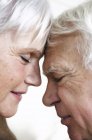 Primer plano de pareja de ancianos cara a cara con los ojos cerrados - foto de stock