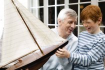 Старший чоловік і хлопчик тримають модель човна на відкритому повітрі — стокове фото