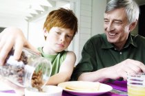 Hombre y niño mayores desayunando en la cocina - foto de stock