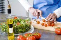 Frau macht Salat, schneidet Tomaten, konzentriert sich selektiv — Stockfoto