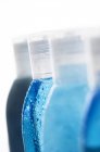 Primer plano de las botellas azules con gotas de agua sobre fondo blanco - foto de stock