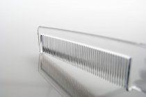 Primer plano del peine de plástico transparente sobre fondo gris - foto de stock