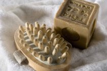 Close-up de sabão e massageador de madeira na toalha branca — Fotografia de Stock
