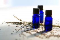 Primer plano de botellas de aceite esencial azul y granos secos - foto de stock