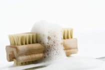 Primer plano de cepillo de uñas con espuma de jabón sobre fondo blanco - foto de stock