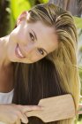 Портрет усміхненої молодої жінки чистить волосся на відкритому повітрі — стокове фото