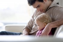 Mann mit kleinem Jungen sitzt auf einem Sofa, Seitenansicht — Stockfoto