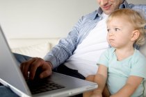 Man and little boy using laptop computer — Stock Photo