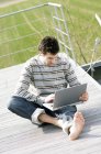 Чоловік сидить на терасі і використовує ноутбук — стокове фото