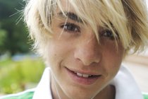 Portrait of smiling blond teenage boy on blurred background — Stock Photo