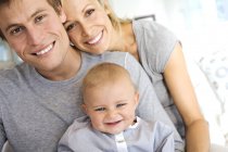 Retrato de padres felices y bebé en casa - foto de stock