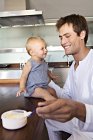 Улыбающиеся отец и малыш, завтракающие на кухне — стоковое фото