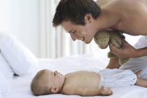 Pai alegre olhando para o bebê deitado na cama — Fotografia de Stock