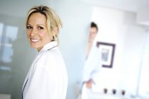 Portrait of smiling young woman in bathrobe with man on background — Stock Photo