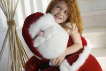 Portrait of ginger little girl holding a cuddly Santa Claus toy — Stock Photo