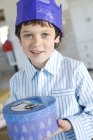 Retrato de um menino abrindo presente em uma caixa azul, dentro de casa — Fotografia de Stock