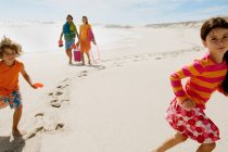 Parents et deux enfants marchant sur la plage, en plein air — Photo de stock