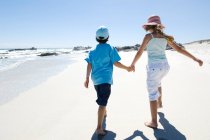 Brother and sister walking on the beach, rear view, outdoors — Stock Photo
