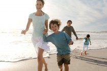 Pais e duas crianças caminhando na praia, ao ar livre — Fotografia de Stock